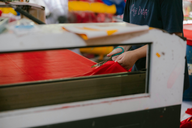 A woman cutting a sheet of fabric with scissors
