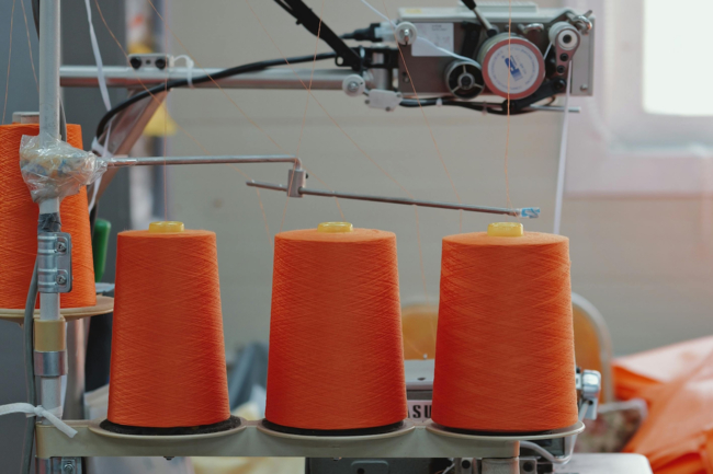 spools of orange fabric on a machine