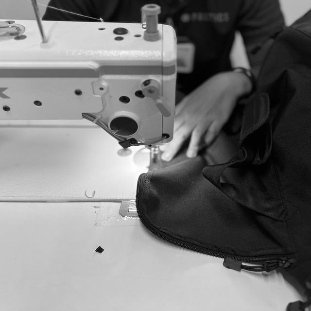 A woman stitching a bag